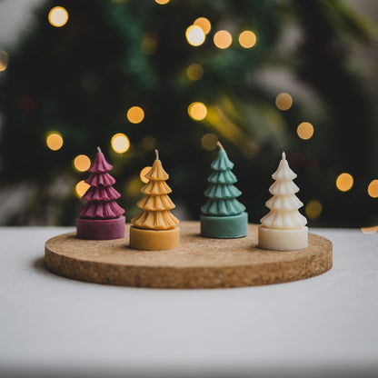 Velas de árbol de Navidad de cera de soya en colores guinda, mostaza, verde y marfil sobre base de corcho.
